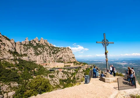 Excursionistes en un camí senyalitzat pel Parc Natural de Montserrat amb cims de roca al fons